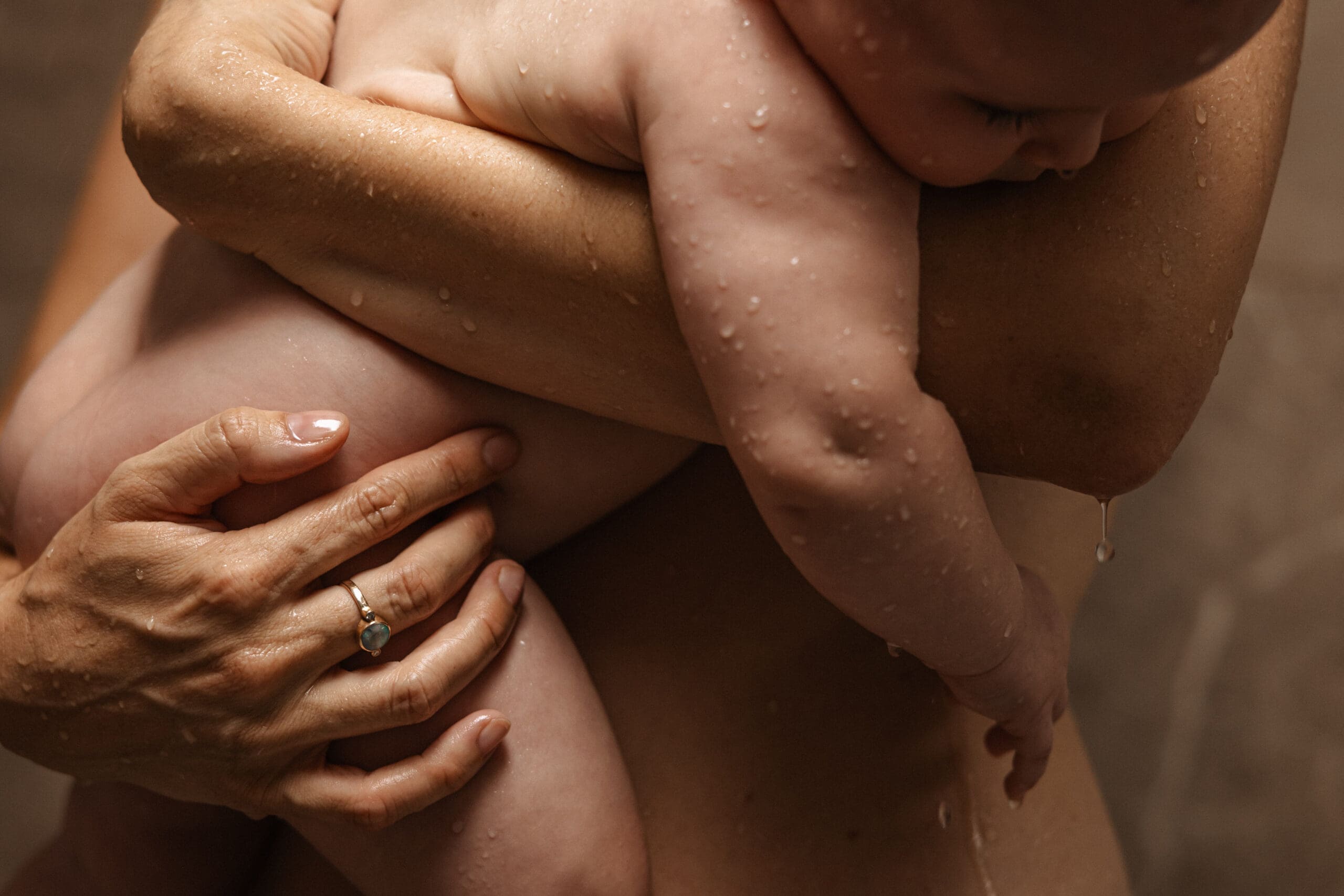 mother holding baby daughter tenderly in the warm shower