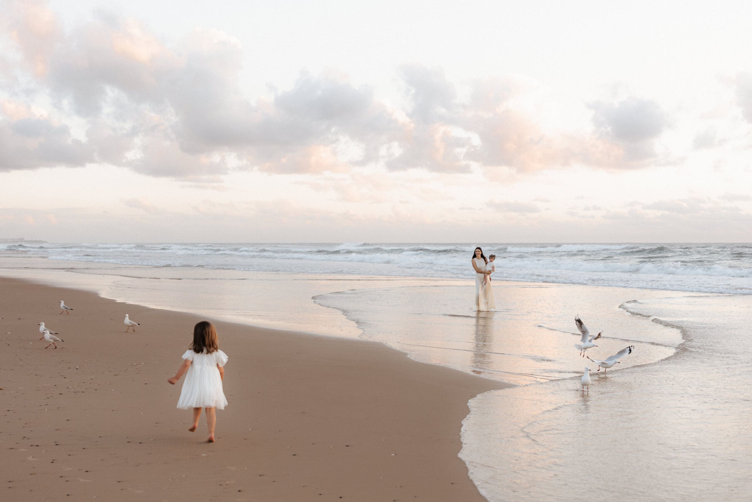 Mother and daughters playing on the beach at sunrise